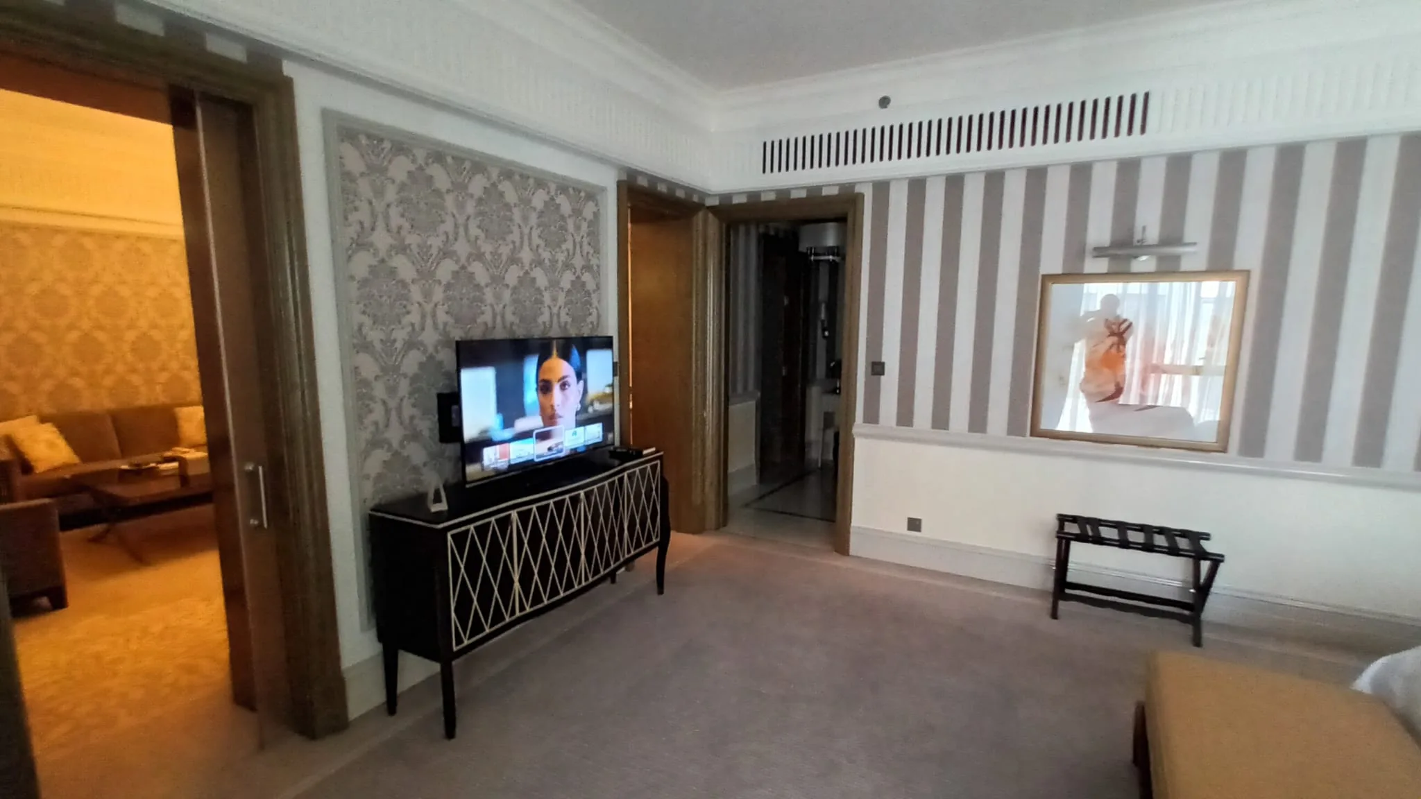 Hotelzimmer mit TV auf Konsole und gestreiftem Wandpaneel