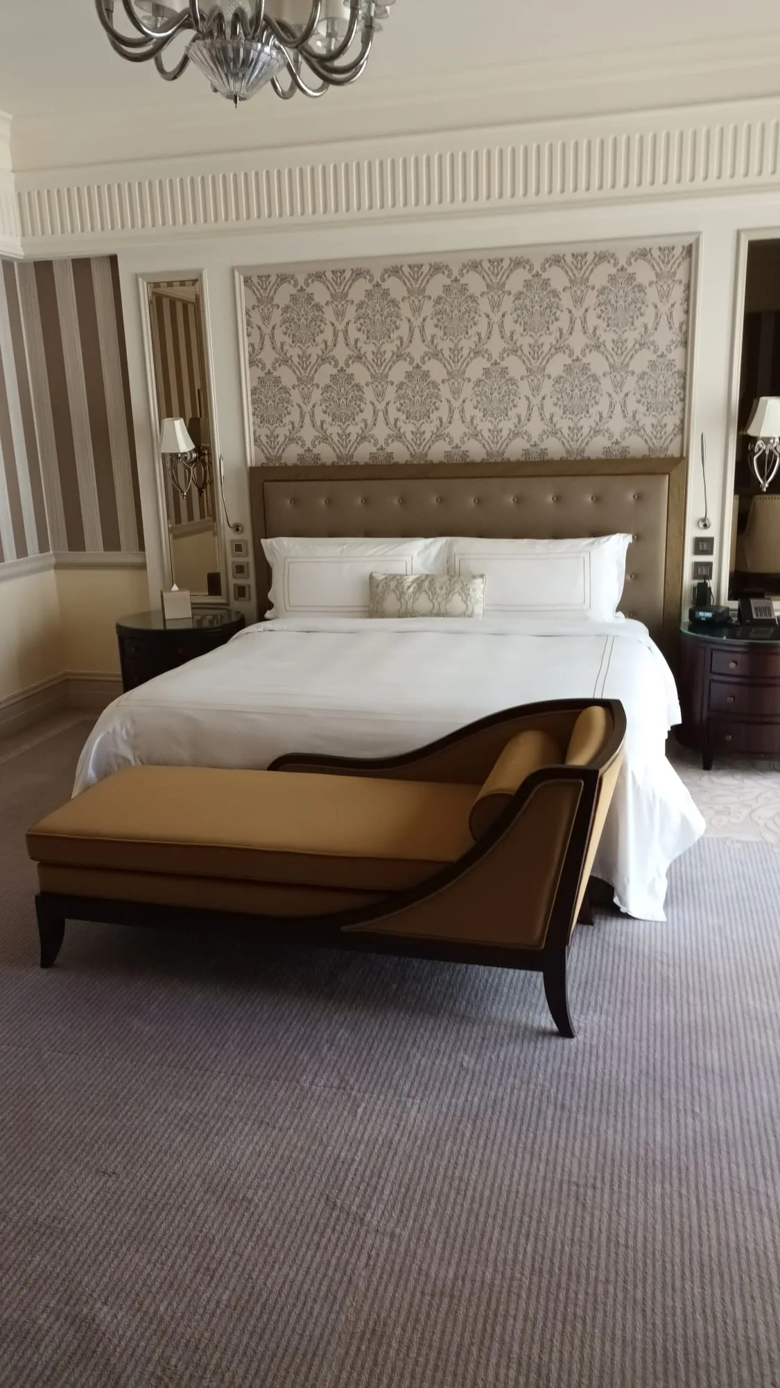 Hotelzimmer mit Doppelbett und Sessel in Grautönen