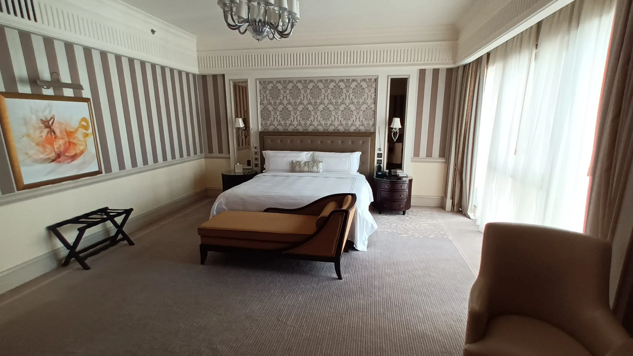 Hotelzimmer mit Doppelbett und Sessel in Grautönen
