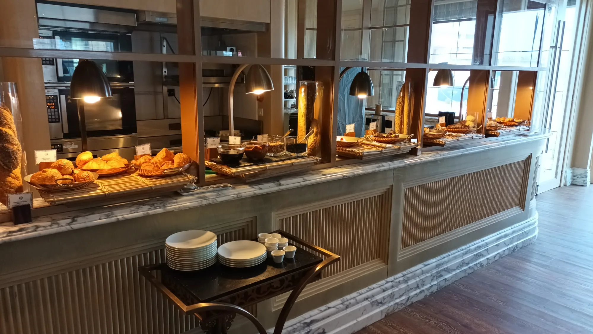 Frühstücksbuffet mit verschiedenen Gebäcksorten und Kaffee auf einer Marmoregal