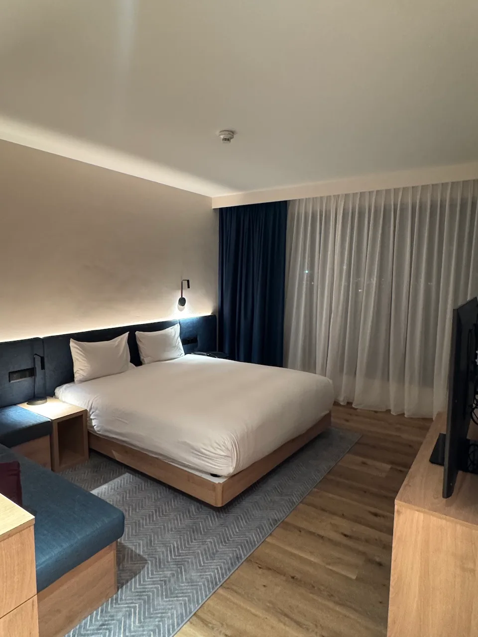 Hotelzimmer mit Doppelbett und Tagesdecke in Grautönen