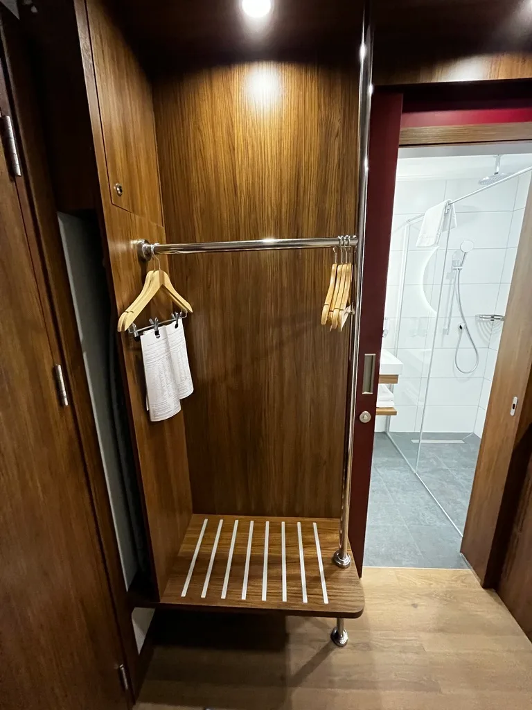 Schrank mit Kleiderbügeln und Handtuch im Hotelzimmer