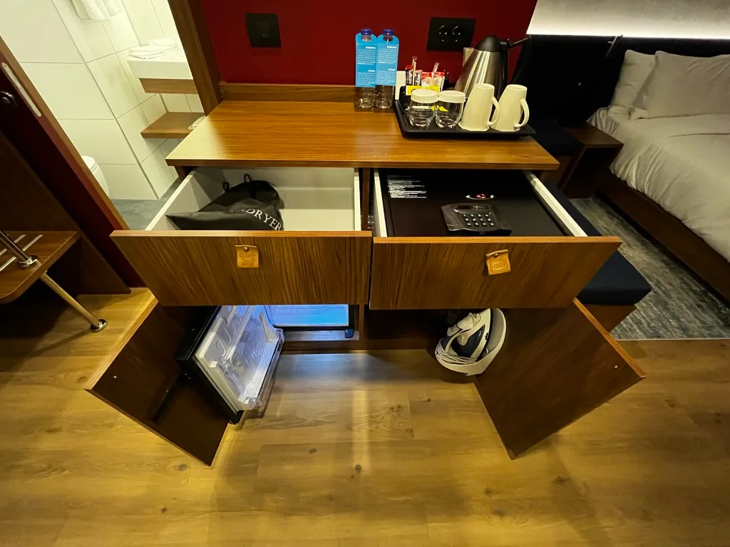 Hotelzimmer mit offenem Schrank und Mini-Kühlschrank