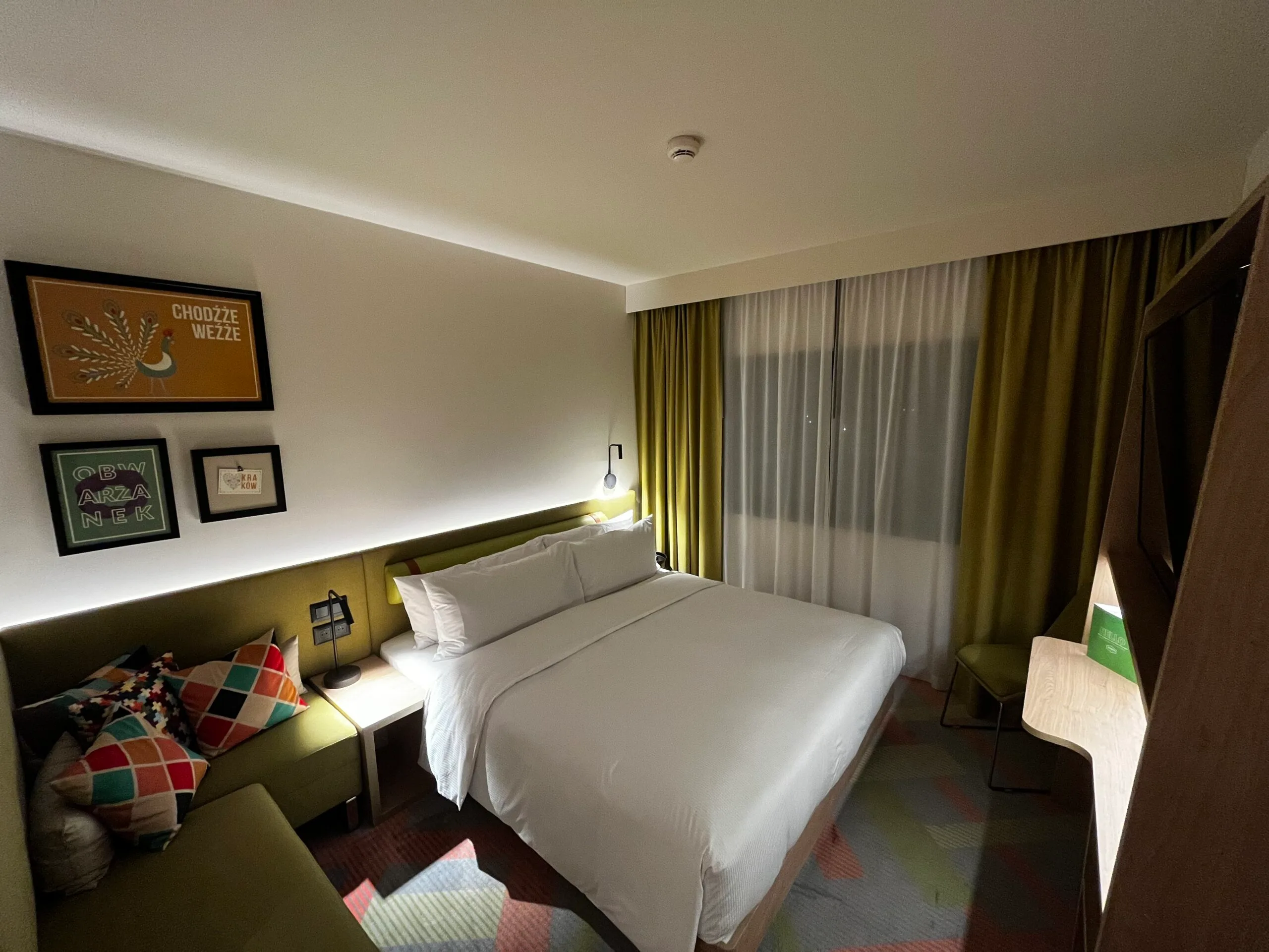 Hotelzimmer mit Doppelbett und grünen Vorhängen