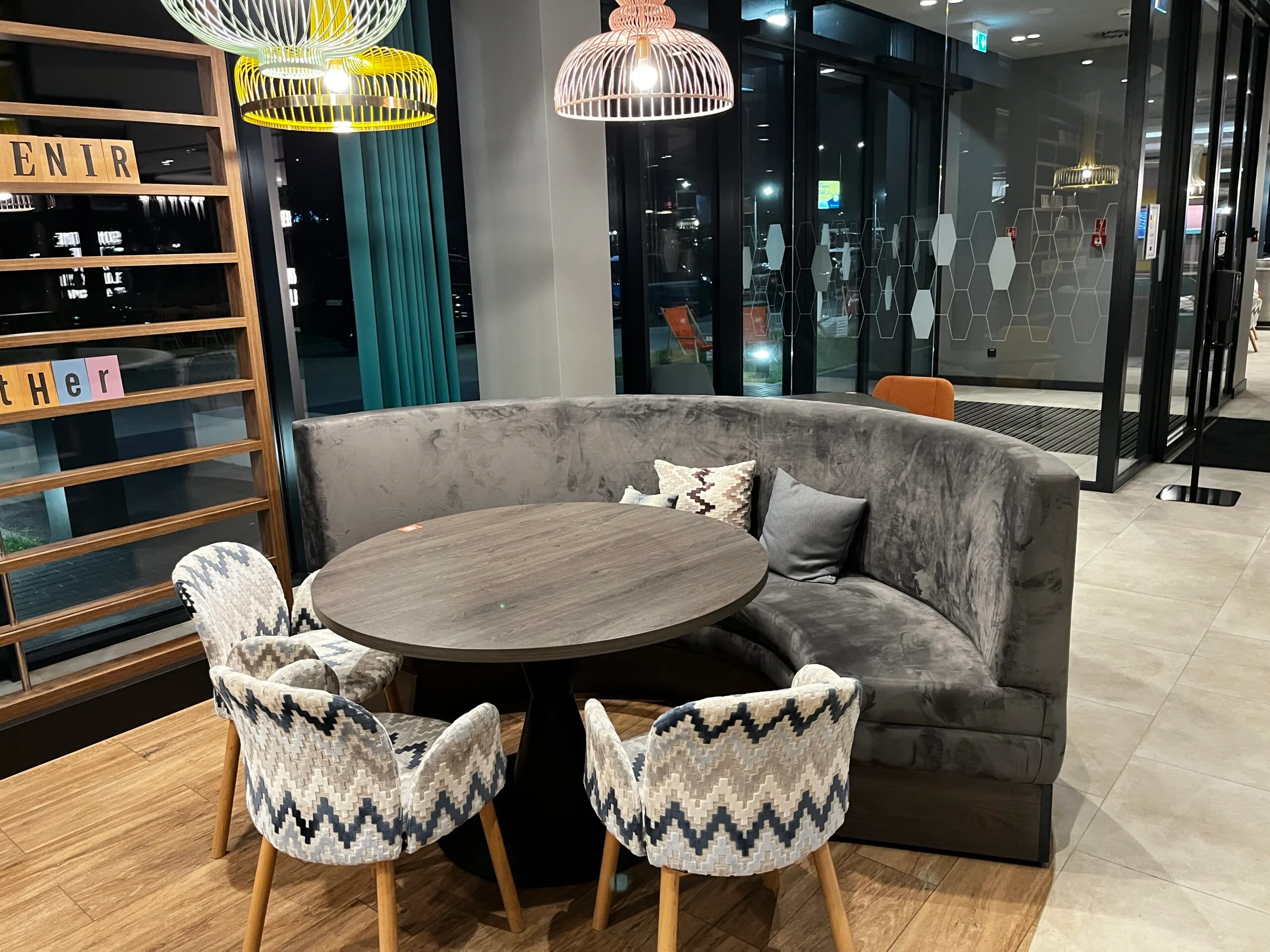 Graues Sofa mit Holztisch und Stühlen im Lobbybereich