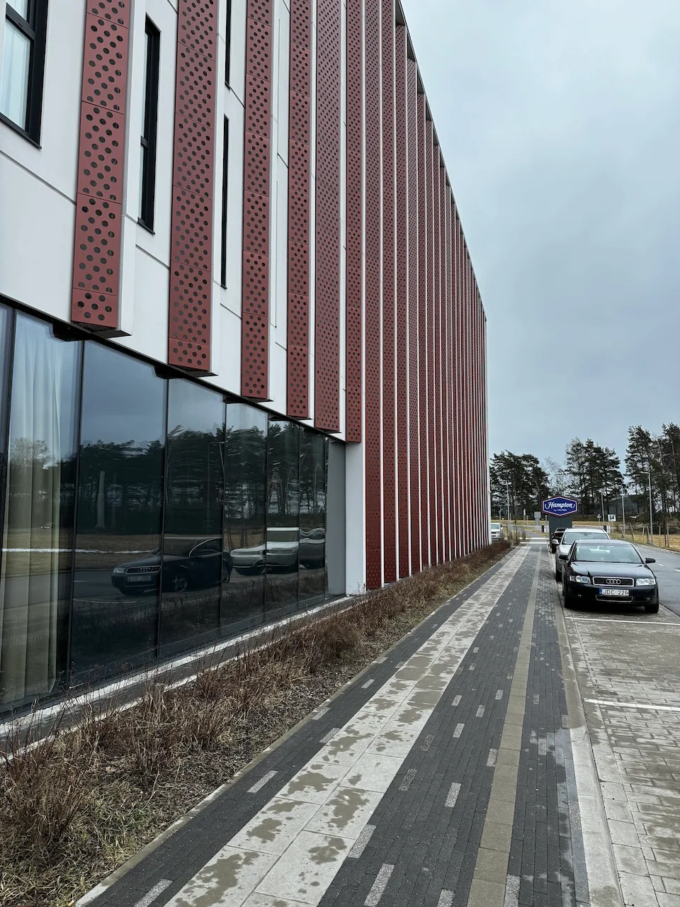 Fassade eines Hotels mit roten Perforationsstreifen und Glasfronten