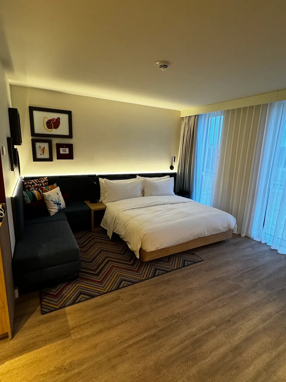 Hotelzimmer mit Doppelbett und Couch in Grautönen