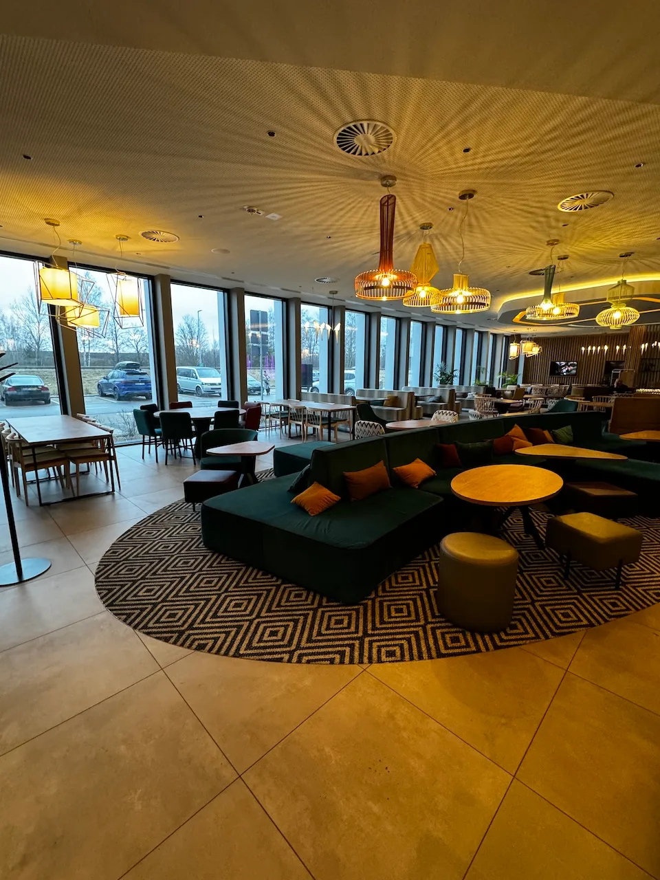 Loungebereich mit grünen Sofas und hängenden Leuchten im Flughafen-Hotel