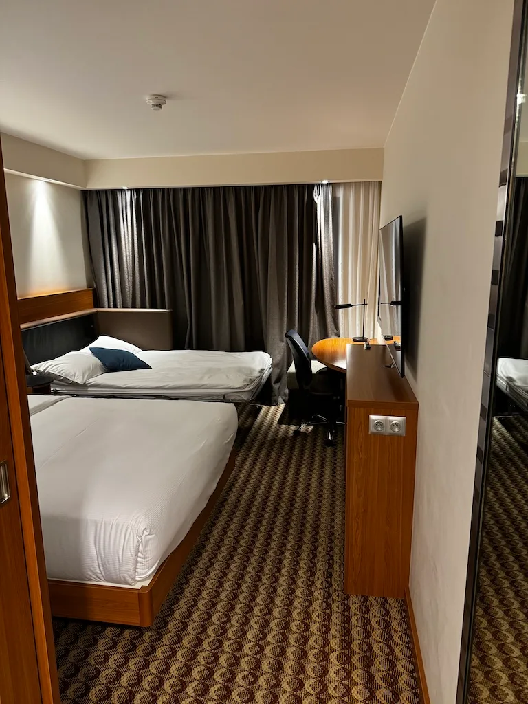 Hotelzimmer mit Doppelbett und Schreibtisch in neutralen Farben
