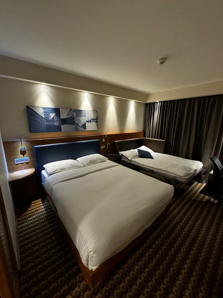 Hotelzimmer mit Doppelbett und Tagesdecke in Grautönen