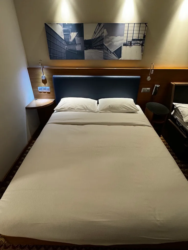 Hotelzimmer mit Doppelbett und grauem Kopfteil
