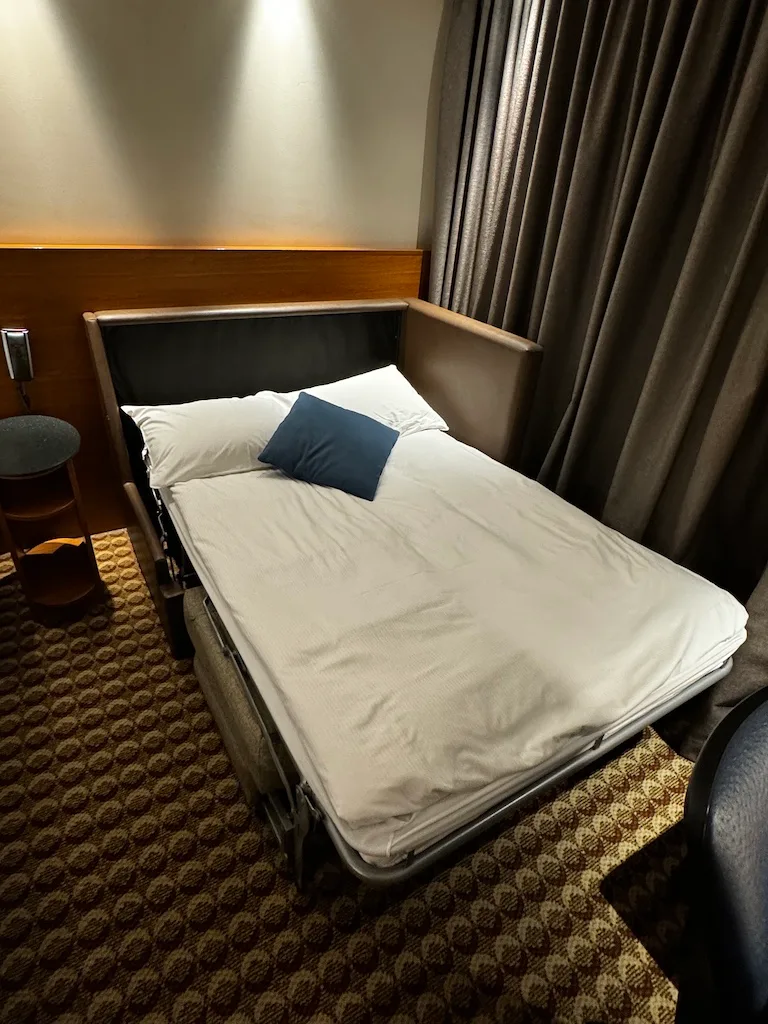 Hotelzimmer mit Doppelbett und Kissen in Grautönen