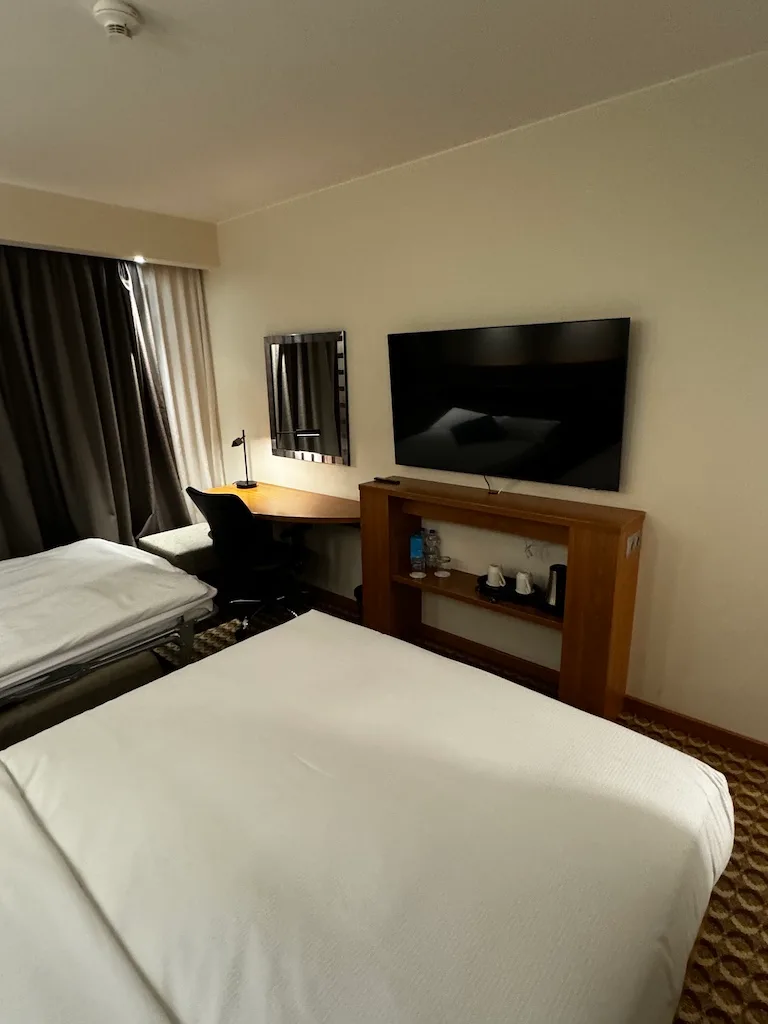 Hotelzimmer mit Doppelbett und Flachbildfernseher an der Wand