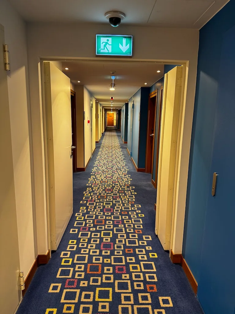 Hotelkorridor mit blauen Wänden und gemustertem Teppich