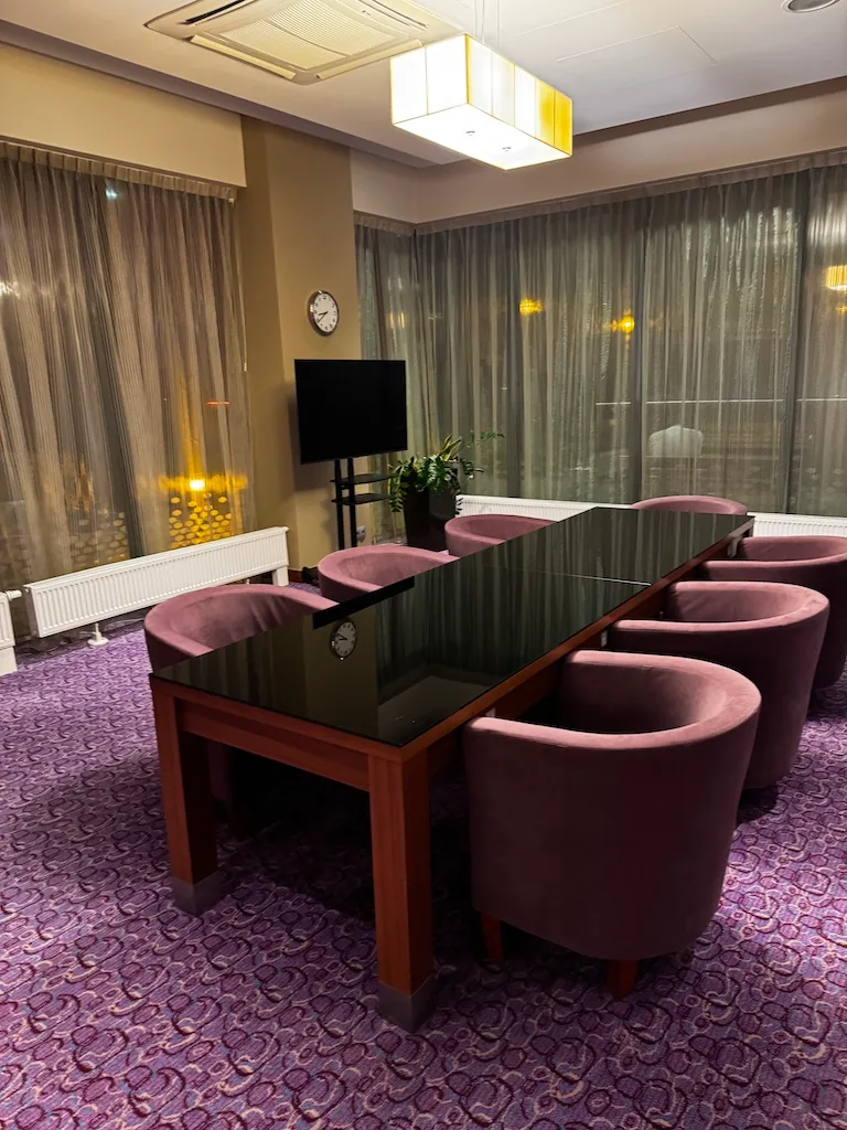 Hotellobby mit langem Tisch und rosa Stühlen
