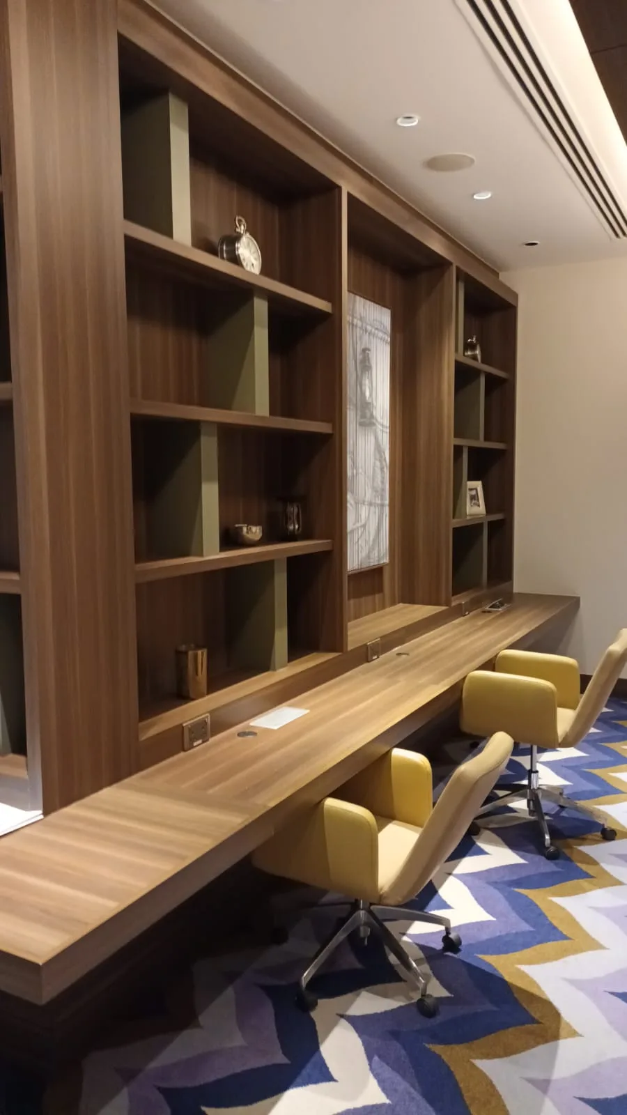 Lounge mit Holzregalen und gelben Stühlen