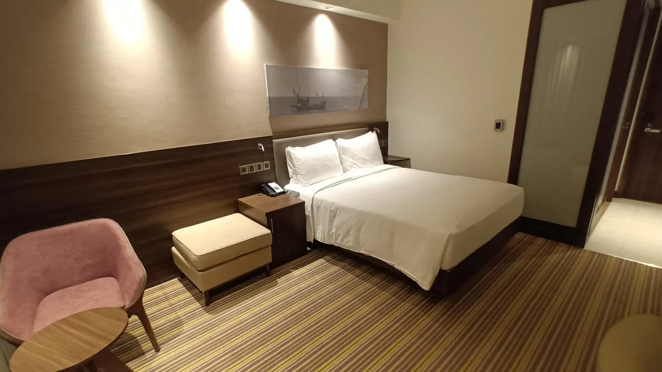 Hotelzimmer mit Doppelbett und Sessel in Grautönen