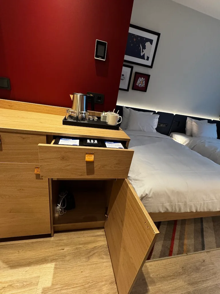 Hotelzimmer mit Doppelbett und Kaffeemaschine auf Holzkommode