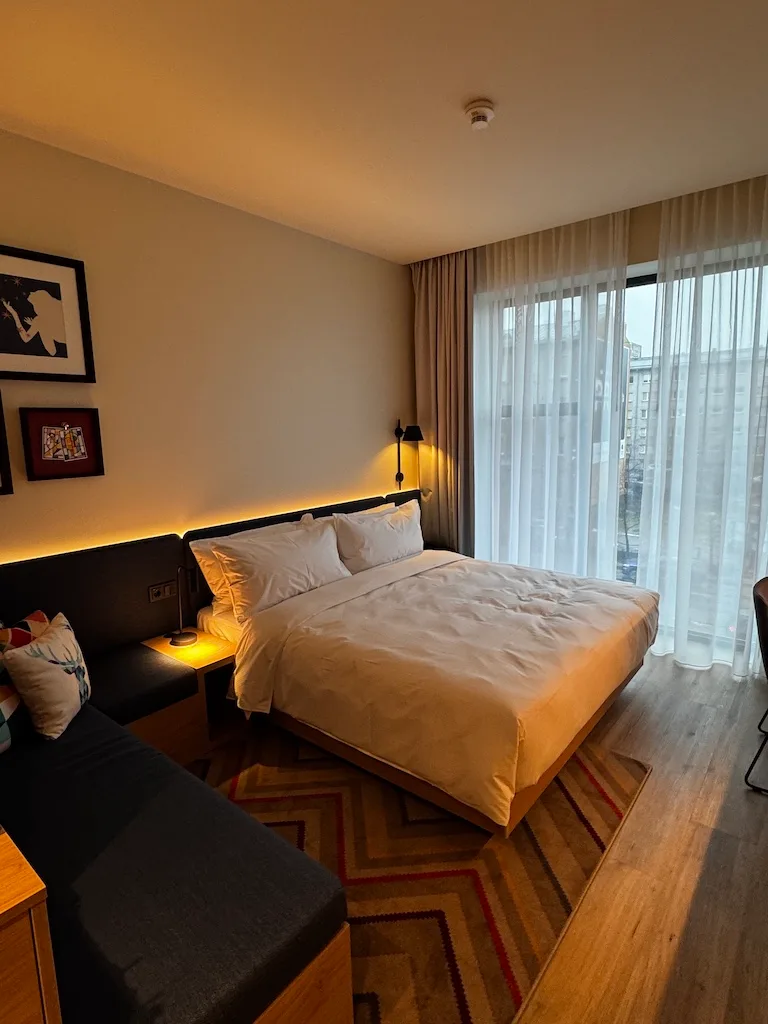 Hotelzimmer mit Doppelbett und Tagesdecke in Grautönen