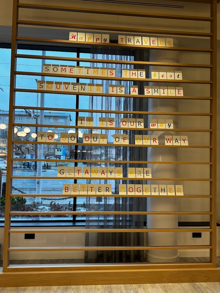Hotellobby mit Holzregal und Reisezitat