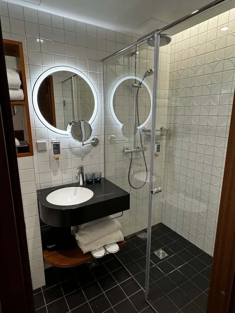 Moderne Badezimmeranlage mit Dusche und rundem Spiegel