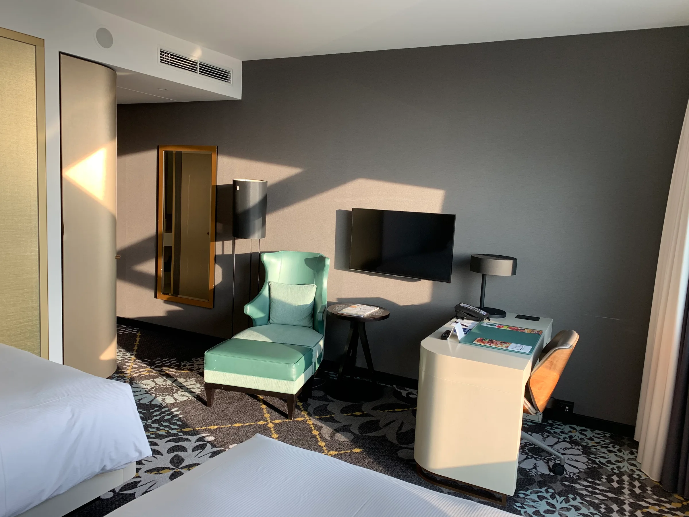Hotelzimmer mit Doppelbett und Sessel in Pastellfarben