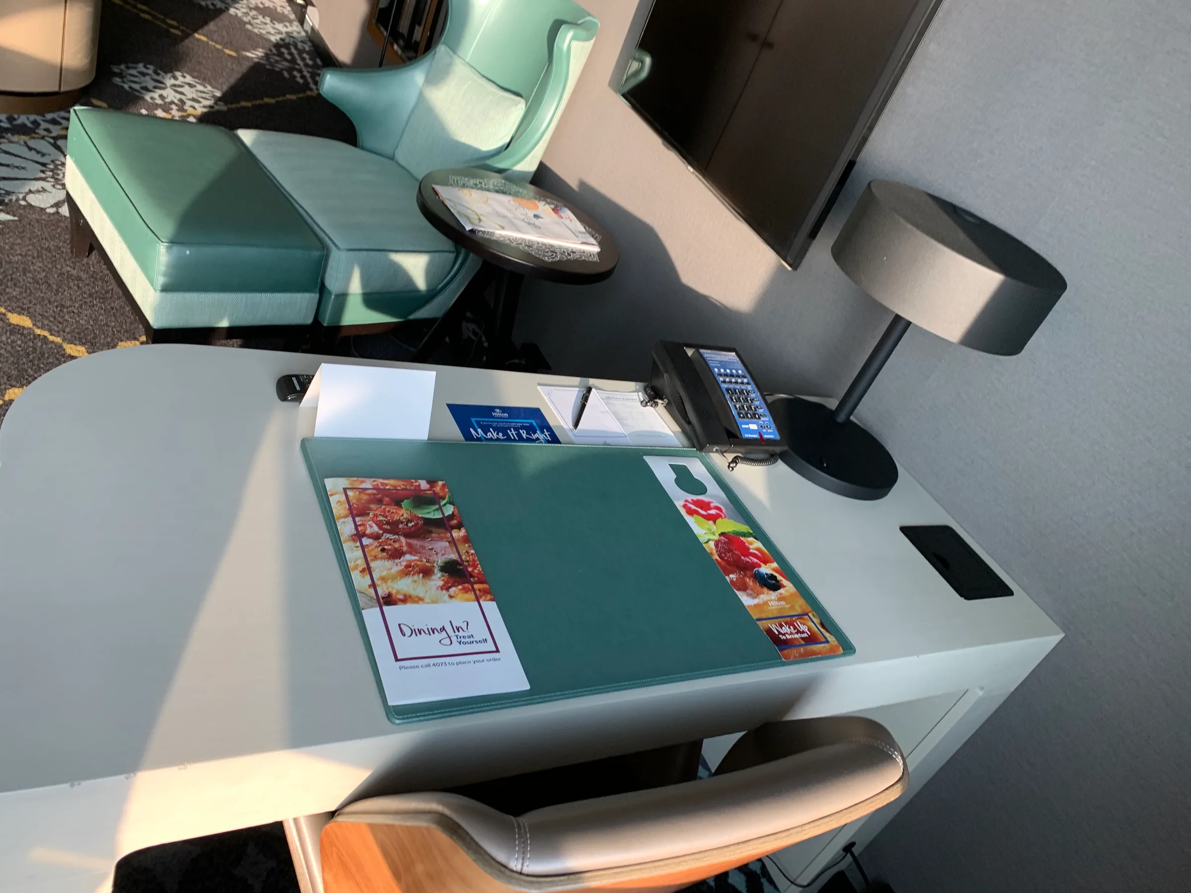 Hotelzimmer mit Schreibtisch, Stuhl und Menü auf Tischplatte