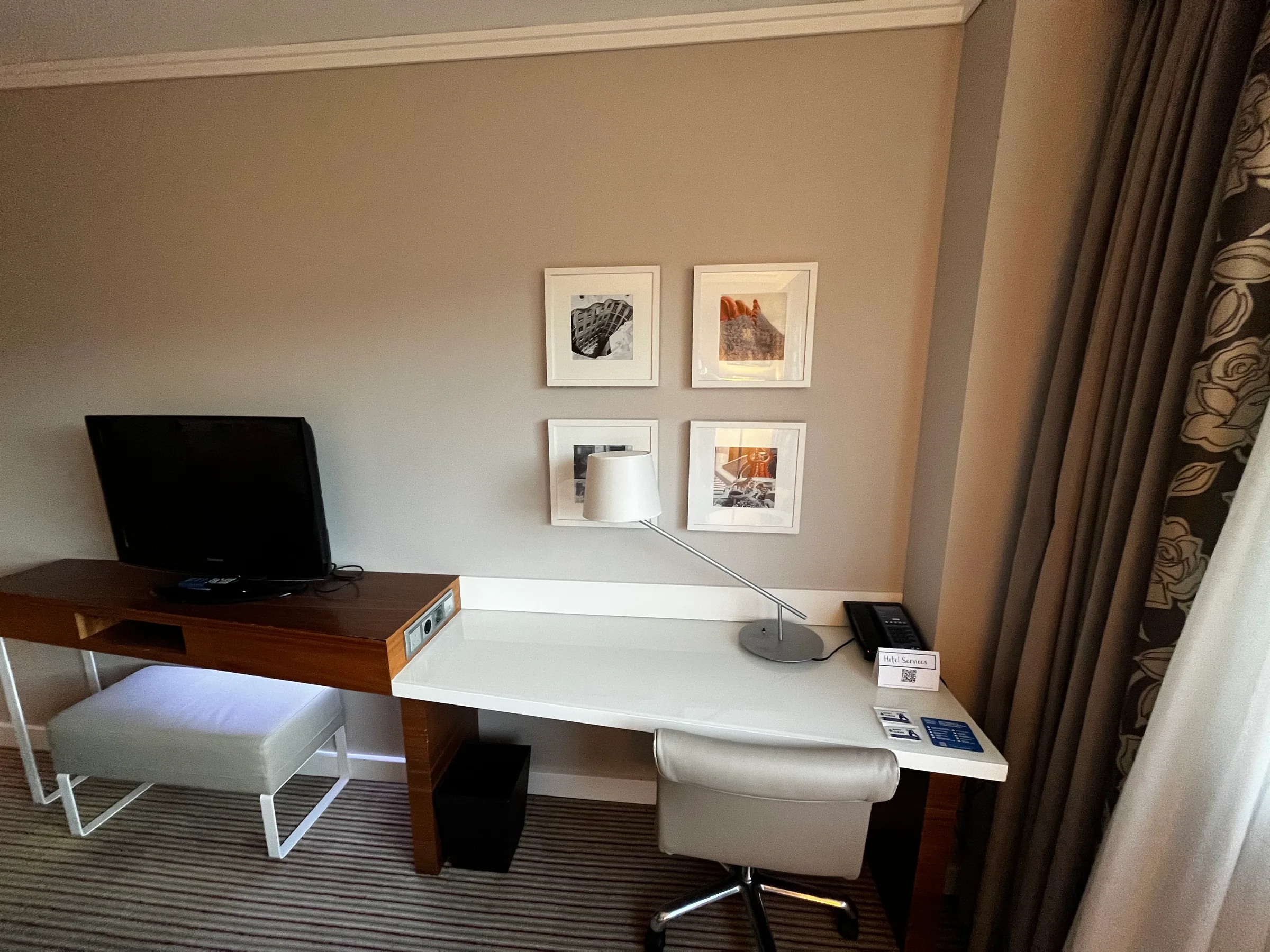 Hotelzimmer mit Schreibtisch, Monitor und Wandbildern