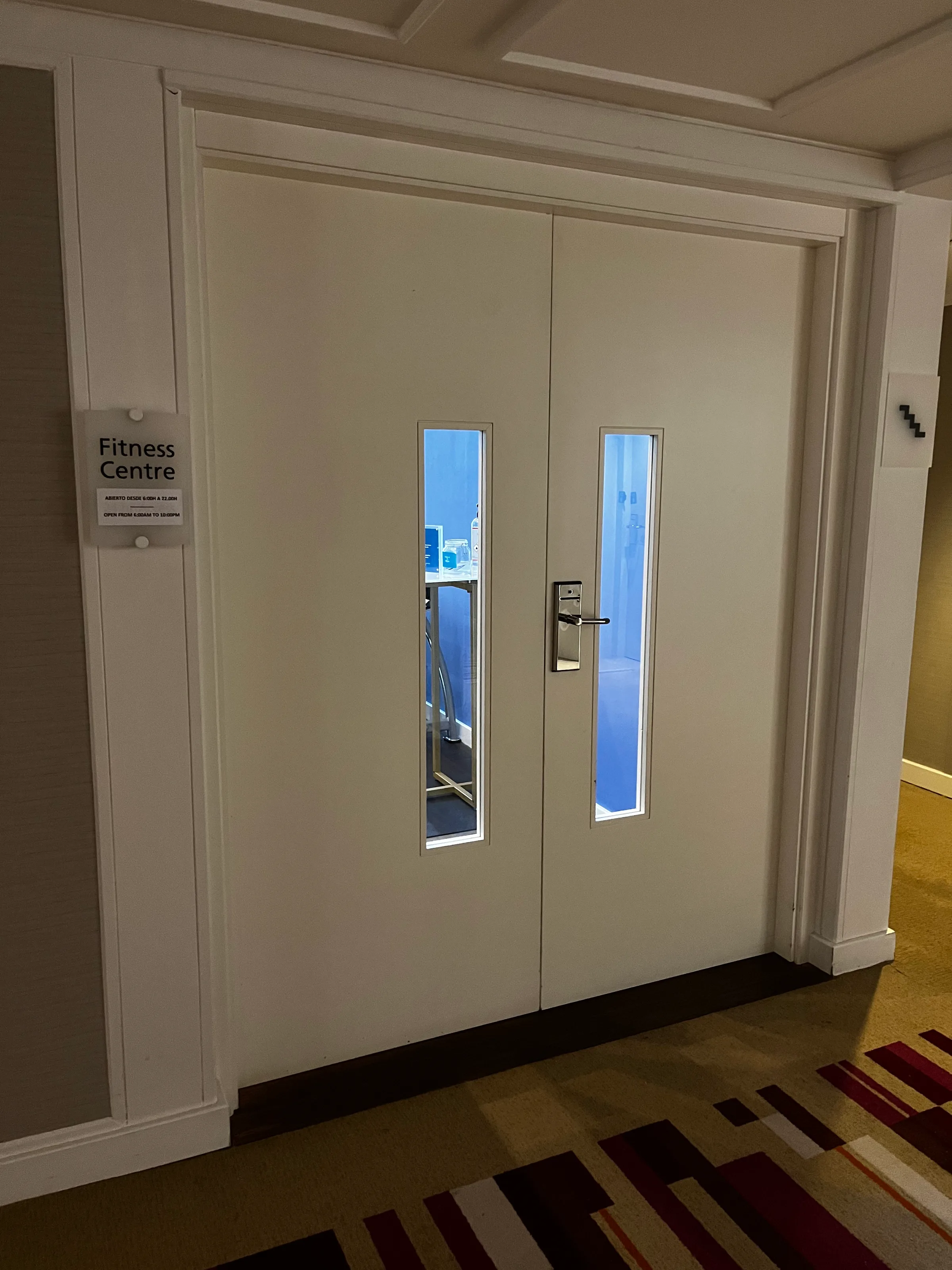Tür zum Fitness-Center mit Schild und Spiegeln