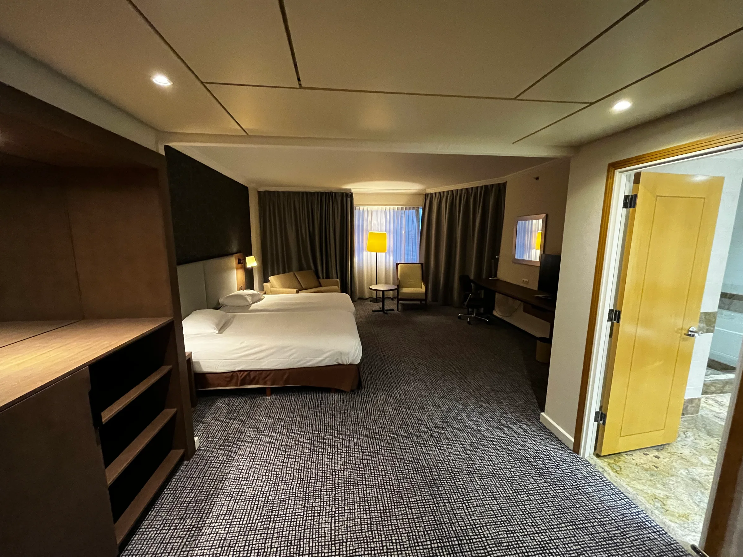 Hotelzimmer mit Doppelbett und Sitzmöbeln in Grautönen