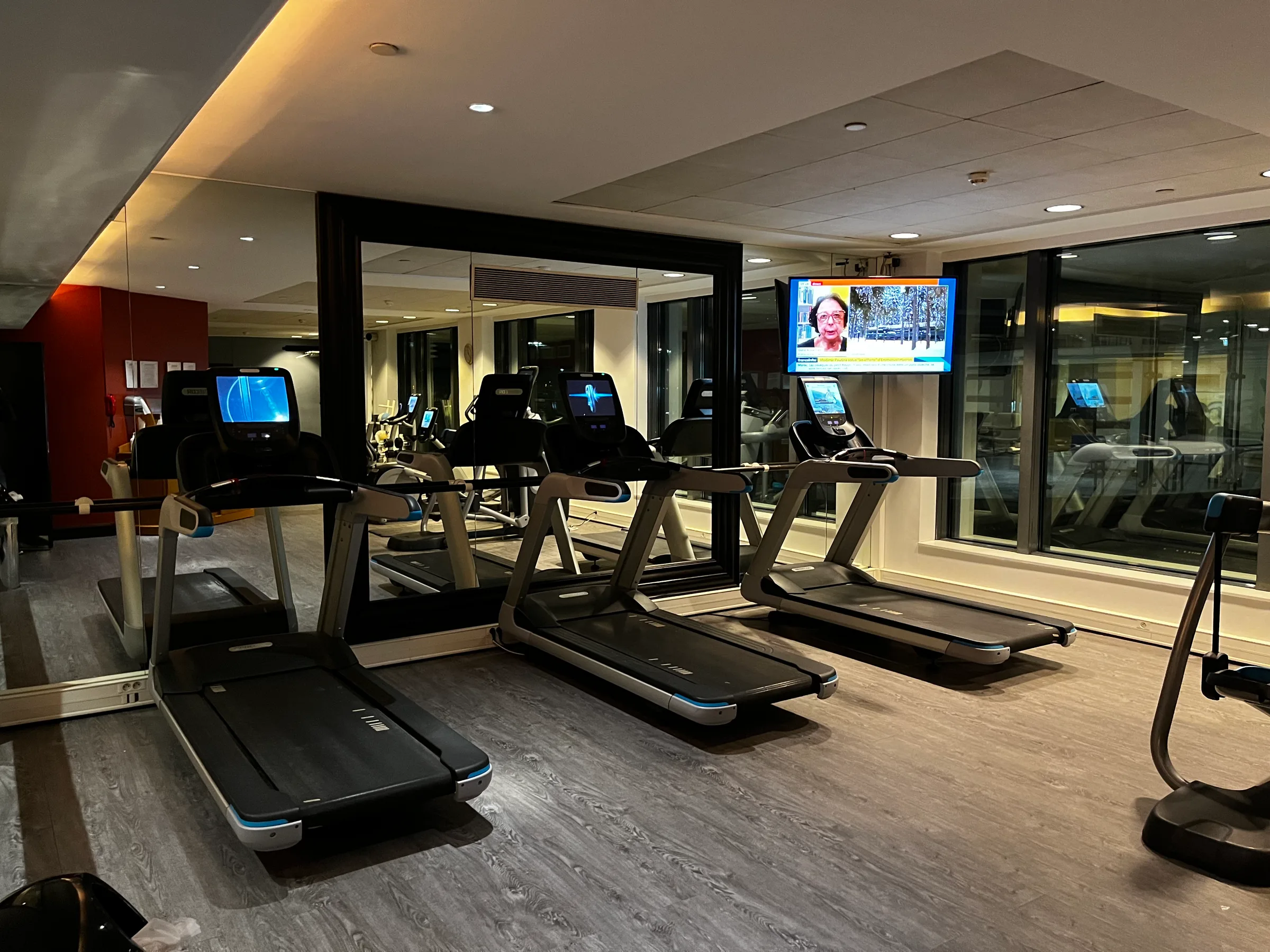 Laufbänder im Fitnessraum mit Spiegeln und Fernseher