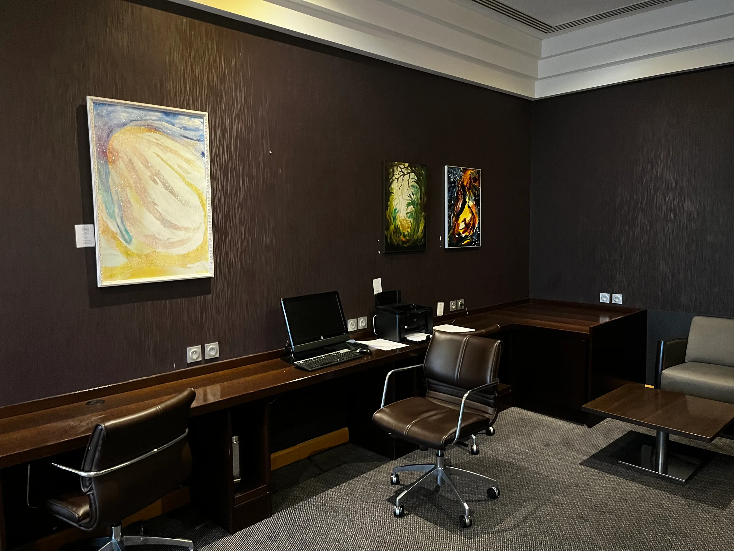 Hotelzimmer mit Schreibtisch, Stühlen und Kunstwerken an der Wand