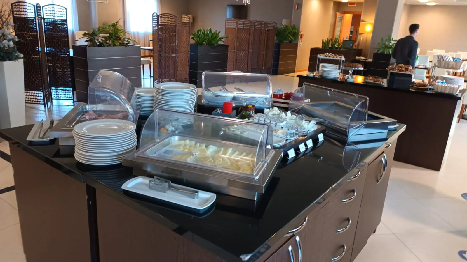 Frühstücksbuffet mit verschiedenen Speisen und Geschirr auf schwarzem Tisch