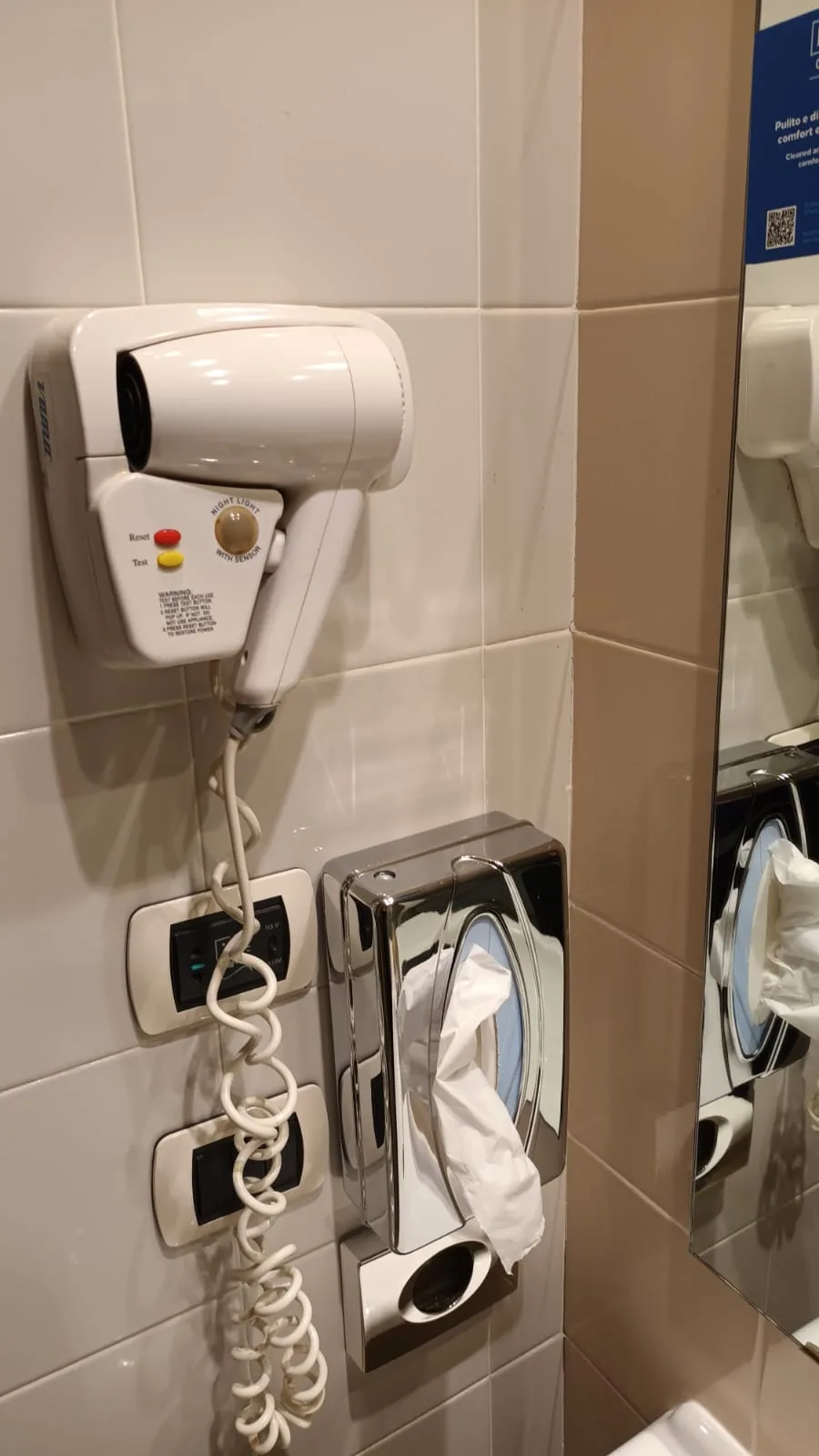 Wandmontierter Haartrockner und Toilettenpapierhalter im Badezimmer