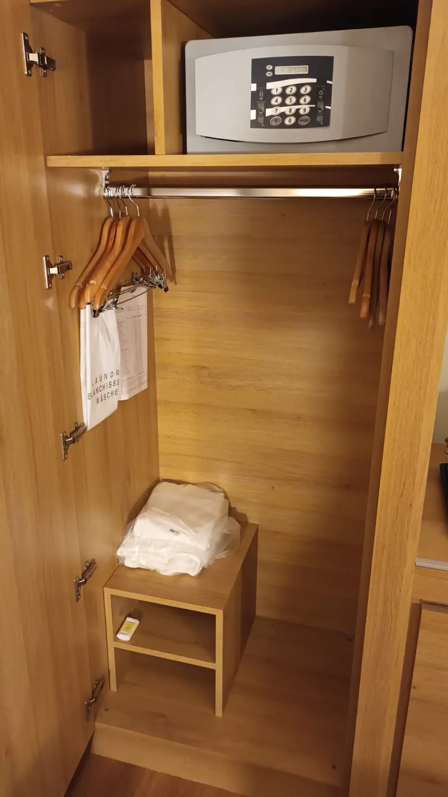 Holzschrank mit Kleiderbügeln und Safe im Hotelzimmer