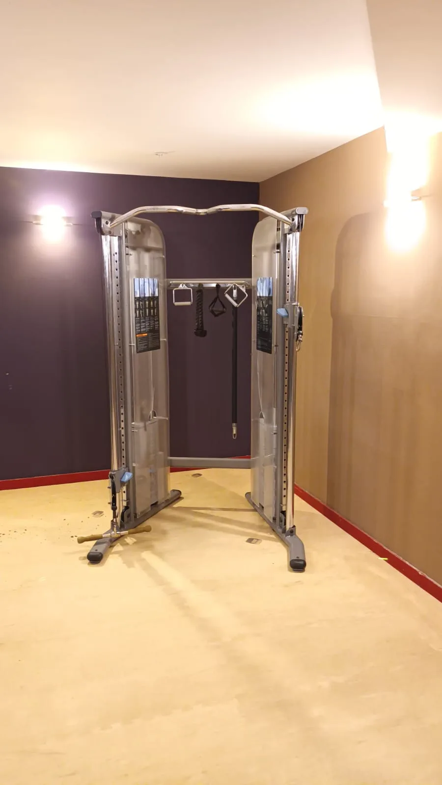 Fitnessgeräte im Hotelgym mit Wandfarben in Lila und Beige