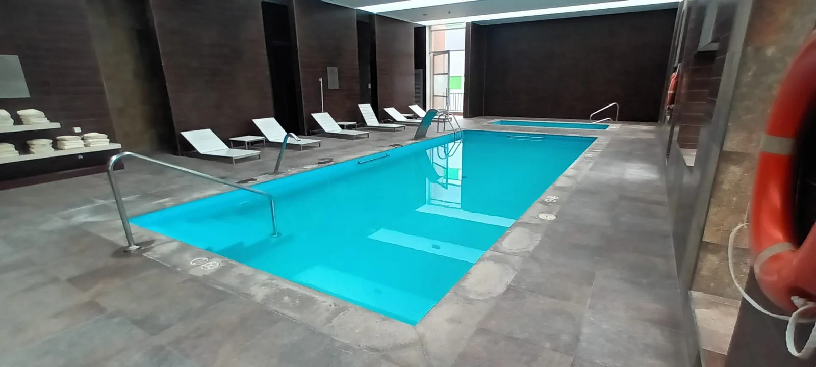 Indoor-Pool mit Liegestühlen und Handtüchern