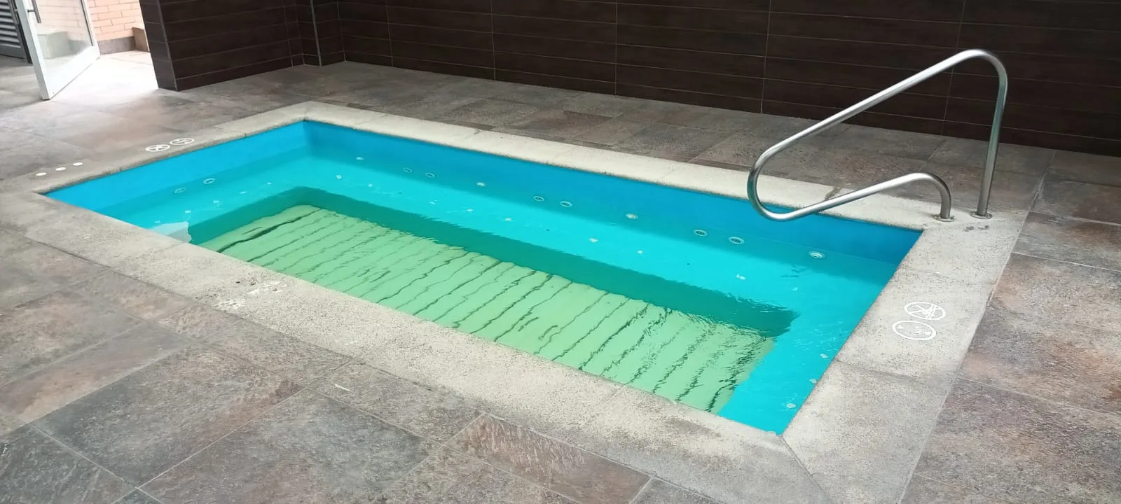 Indoor Whirlpool mit blauem Wasser und Metallgeländer