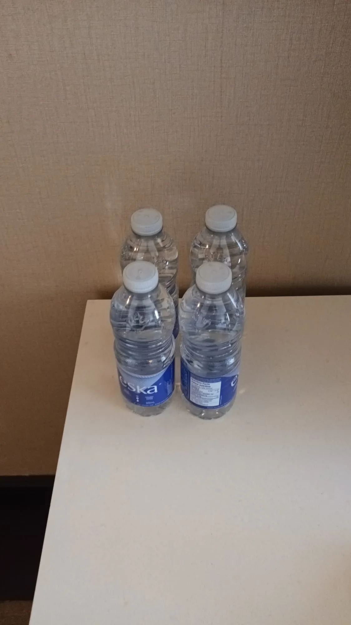 Vier Flaschen Wasser auf weißem Tisch