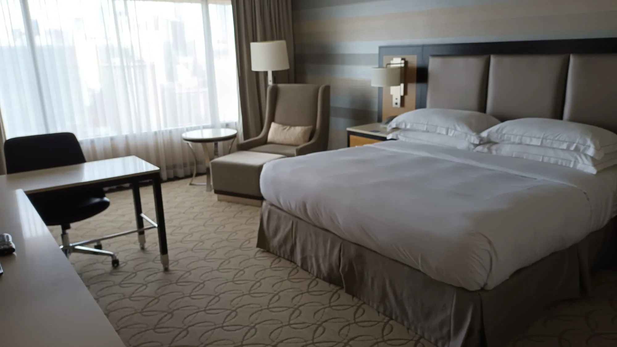 Hotelzimmer mit Doppelbett und Sessel in Grautönen