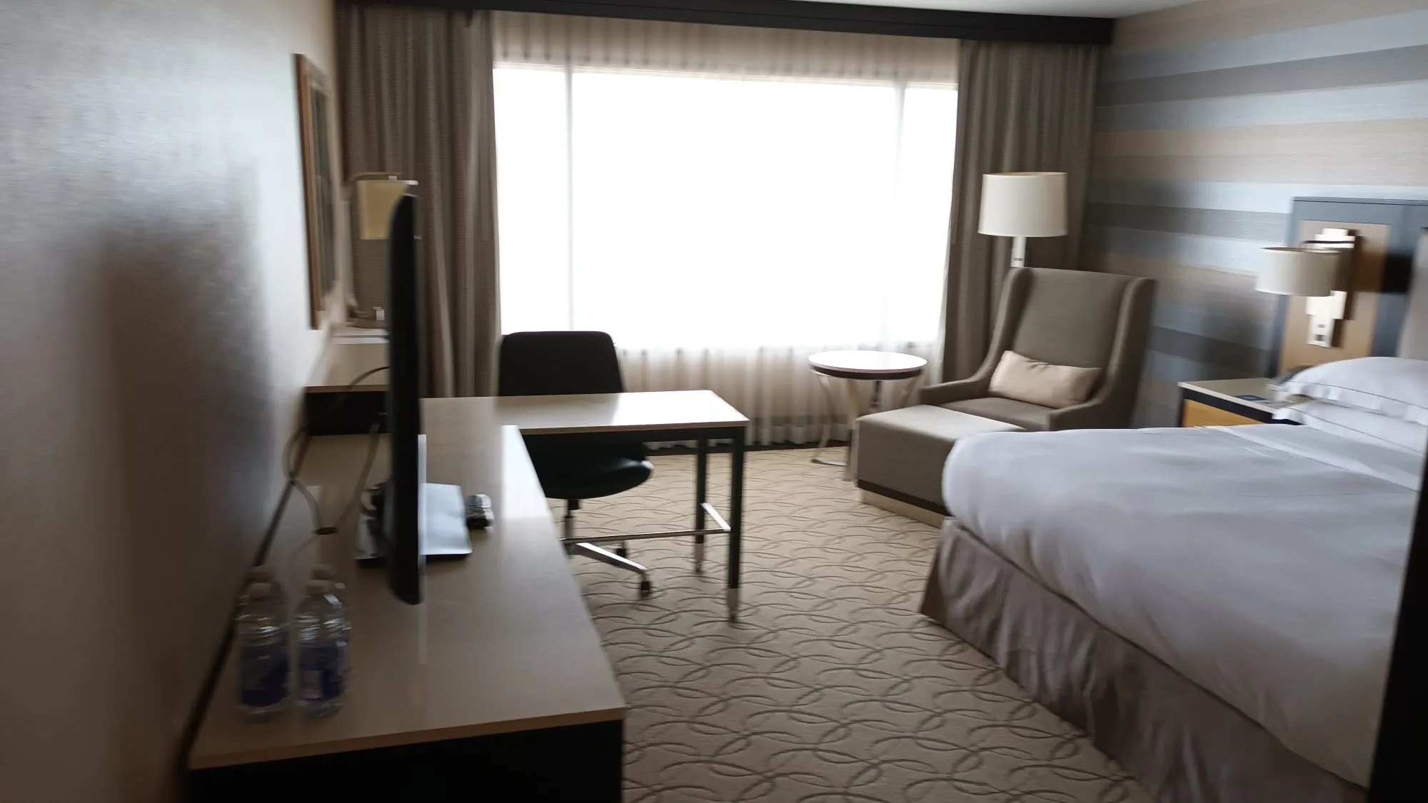 Hotelzimmer mit Doppelbett und Schreibtisch in neutralen Farben