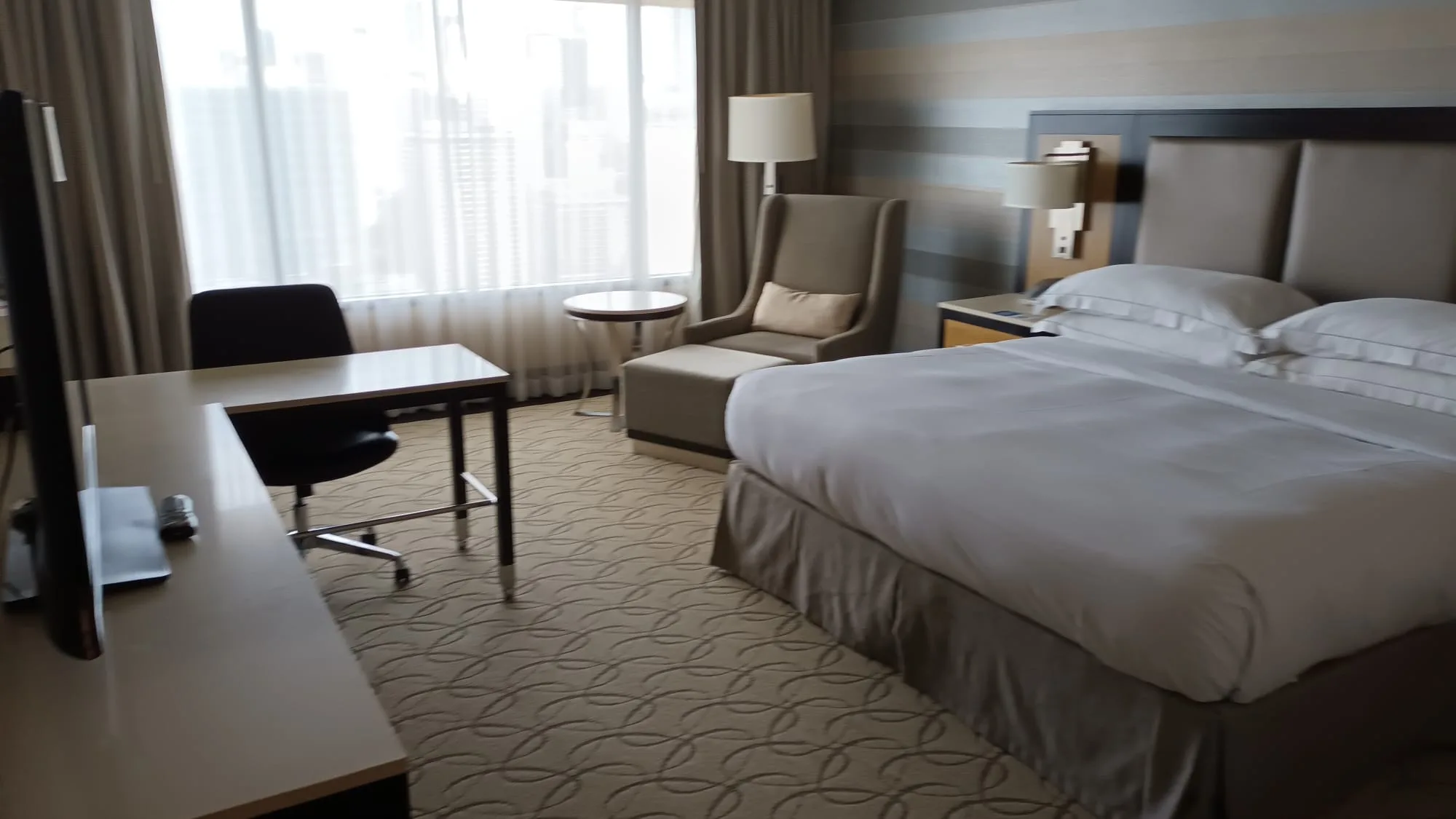 Hotelzimmer mit Doppelbett und Sessel in Grautönen