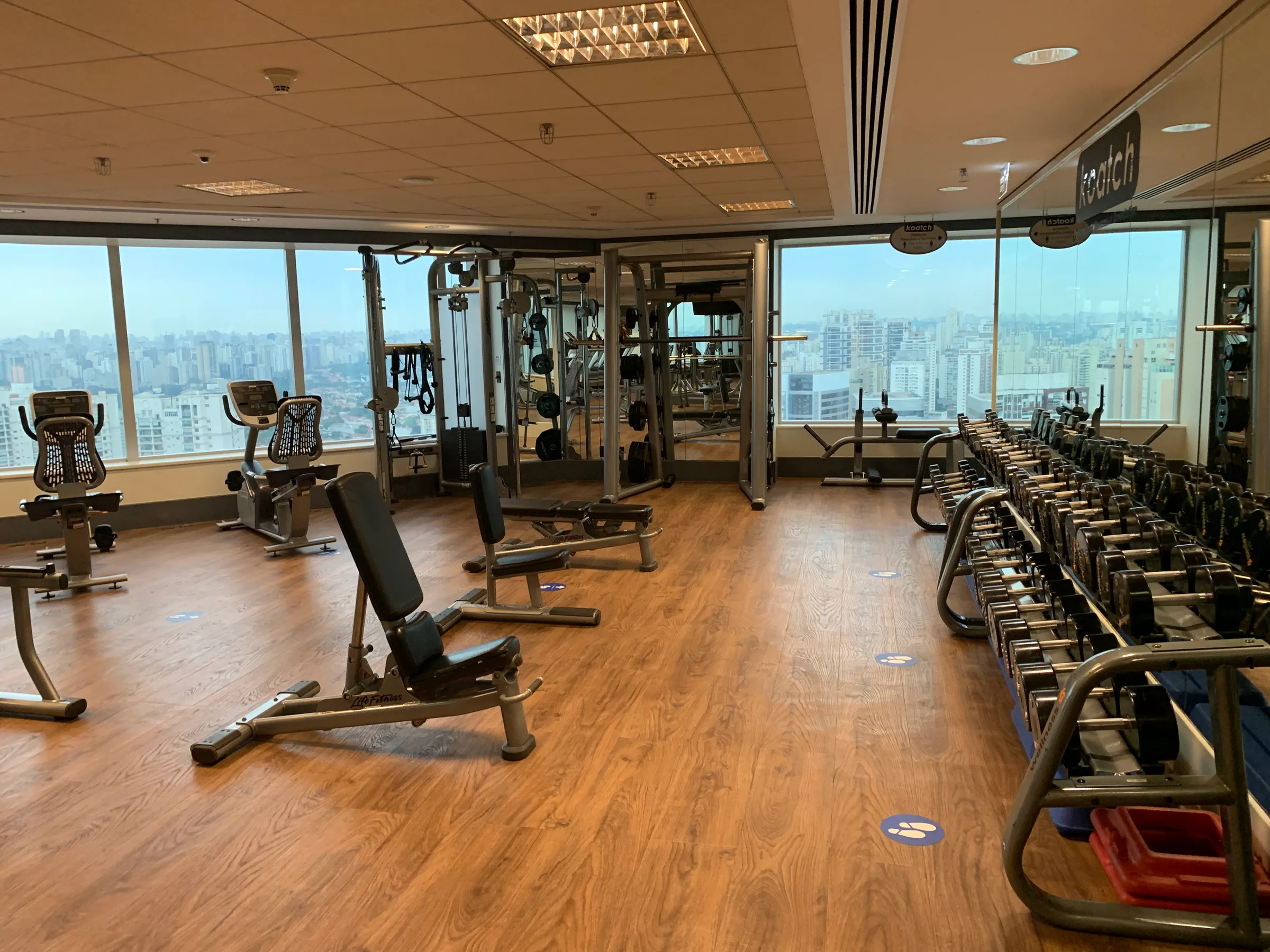 Fitnessraum mit verschiedenen Trainingsgeräten und Blick auf Stadt