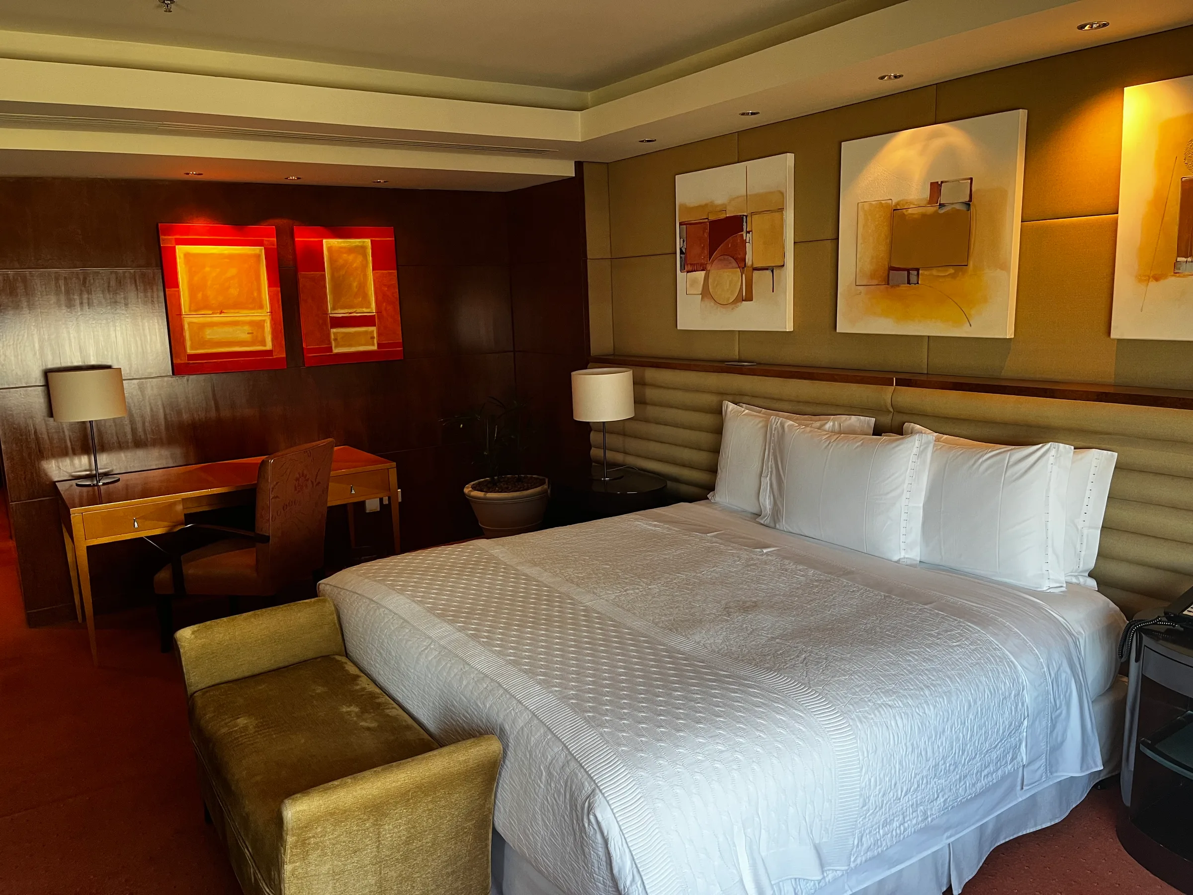 Hotelzimmer mit Doppelbett und abstrakten Gemälden an der Wand