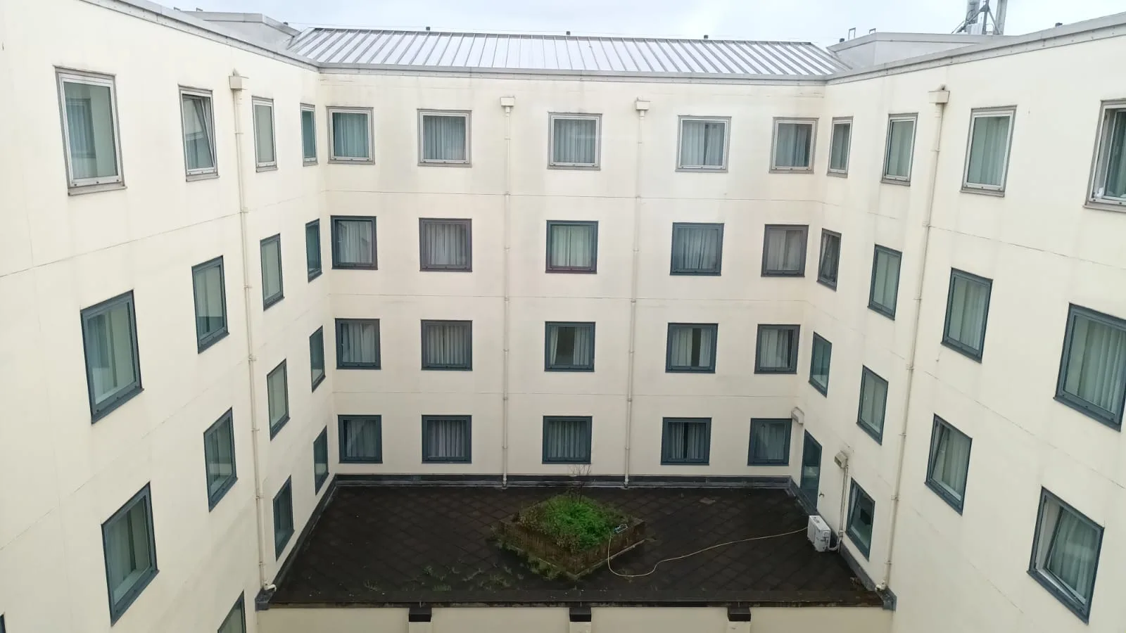 Hotelhof mit vielen Fenstern und begrüntem Zentrum