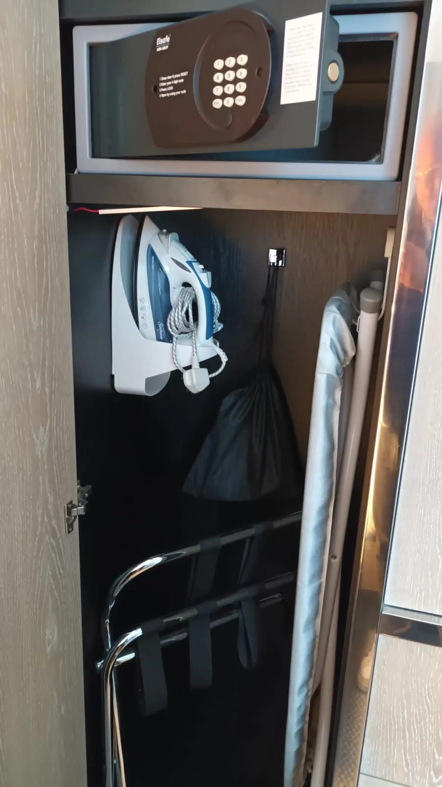Schrank mit Bügeleisen, Regenschirm und Kleiderbügel