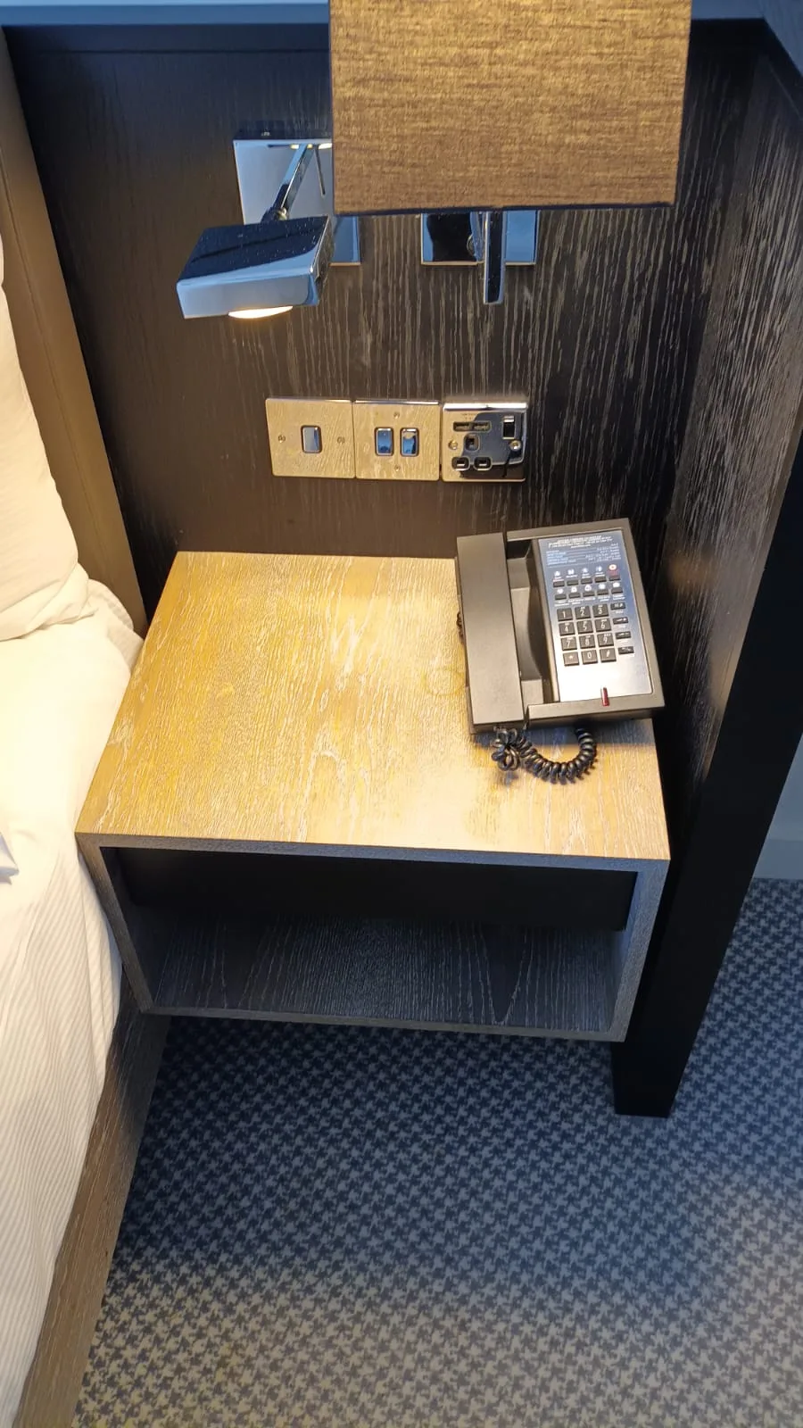 Hotelnachttisch mit Telefon und Steckdosen