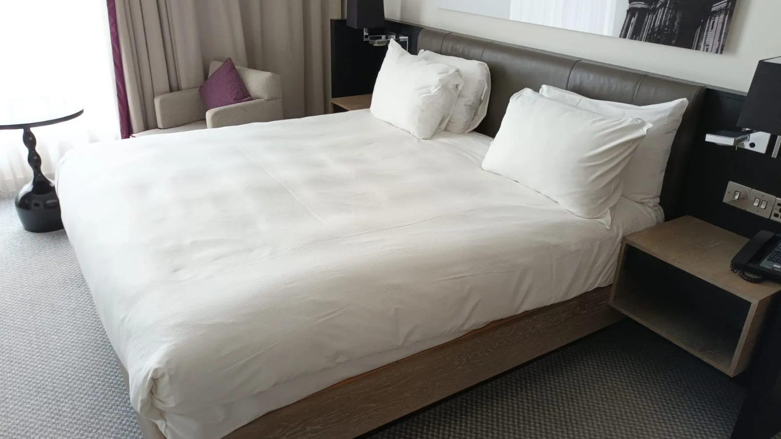 Doppelbett im Hotelzimmer mit grauem Laken