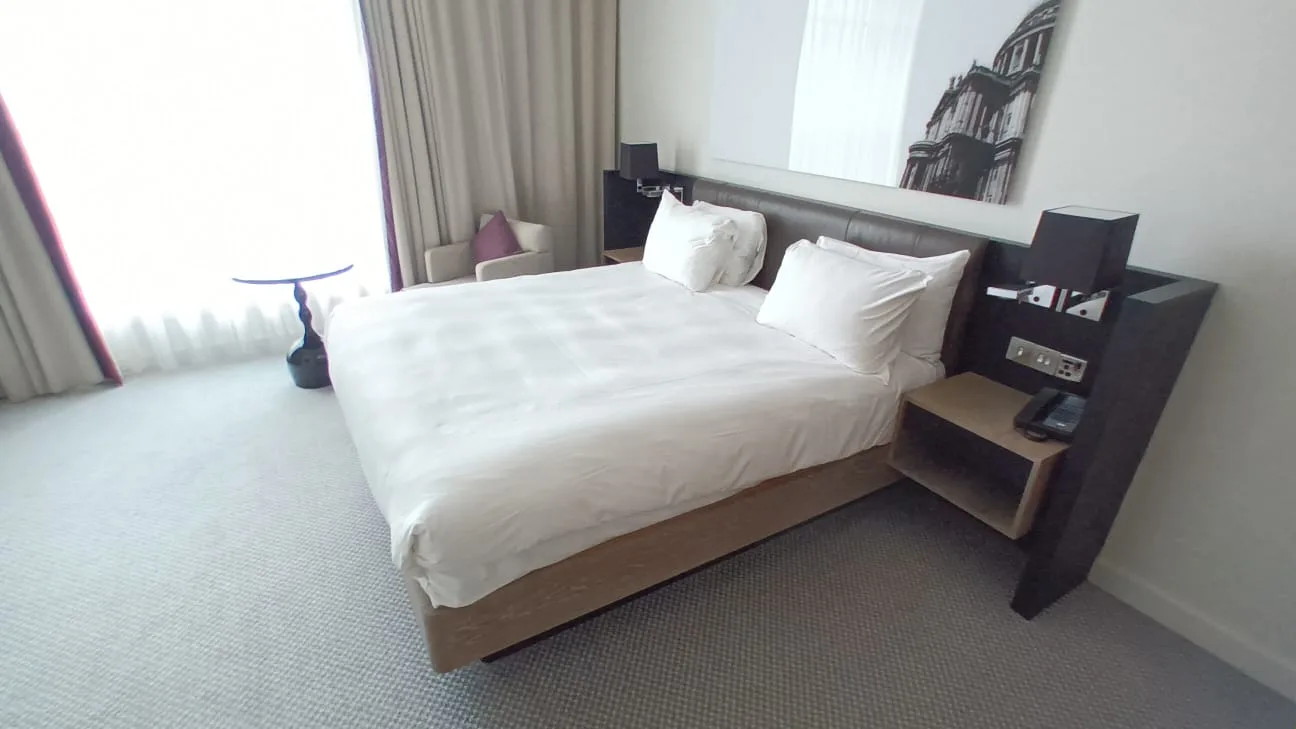 Hotelzimmer mit Doppelbett und Nachttischen in Grautönen