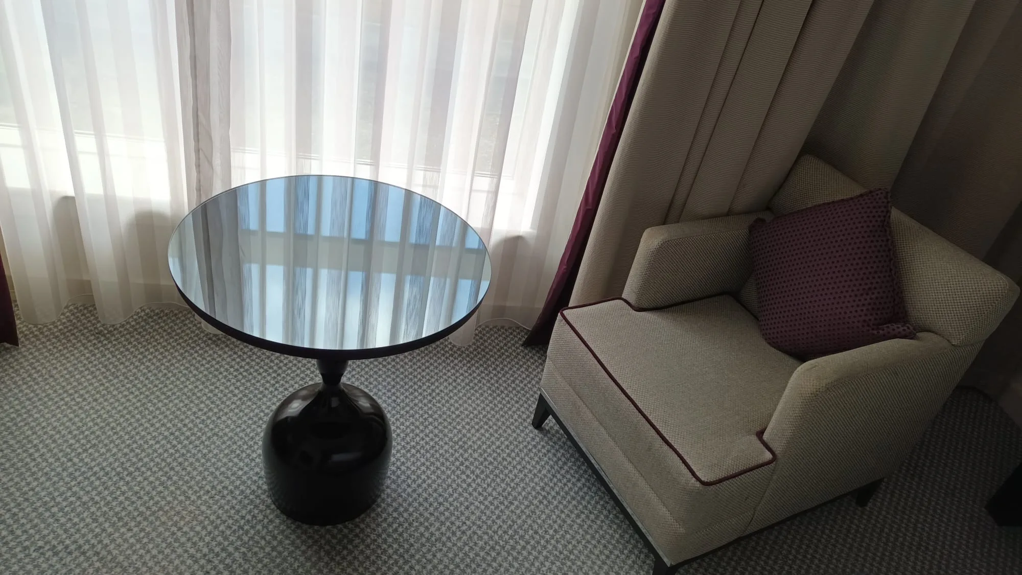 Hotelzimmer mit Sessel und Tisch vor Fenster